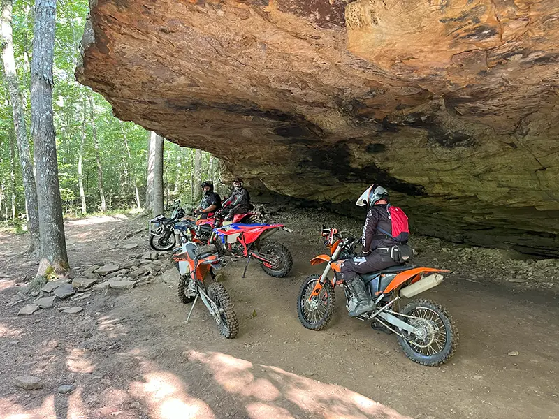 Bikers under a rock ledge