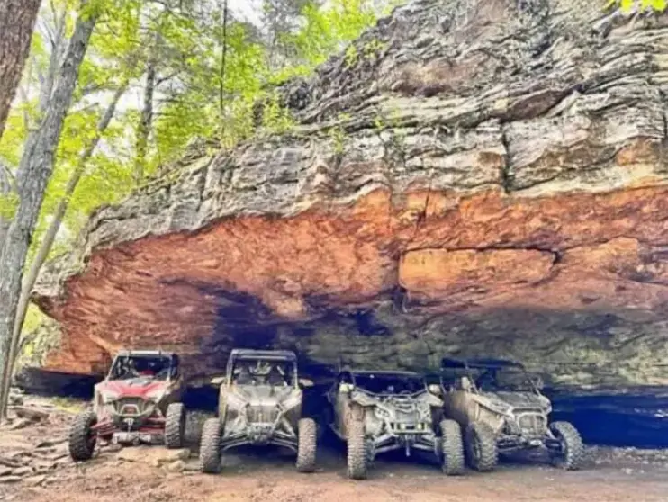 Four wheelers under a cliff