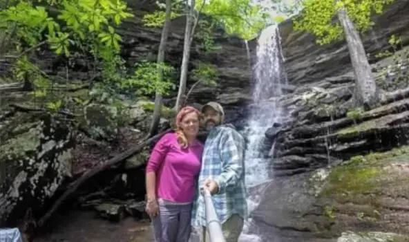 Two people taking a selfie next to a waterfall
